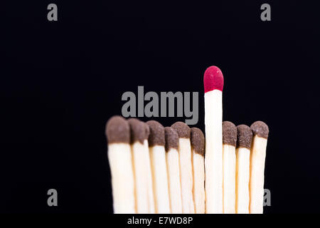 Red headed match standing out from the crowd, leadership concept on dark background. Stock Photo