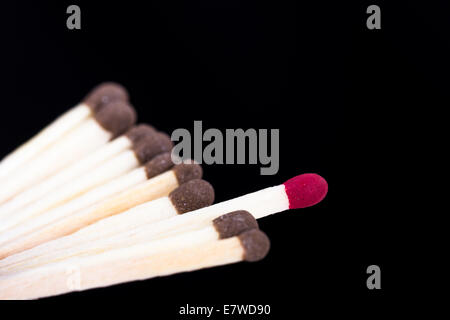 Red headed match against others on dark background. Stock Photo