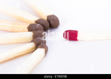 Single red headed match standing out against group of others, isolated on white background. Stock Photo