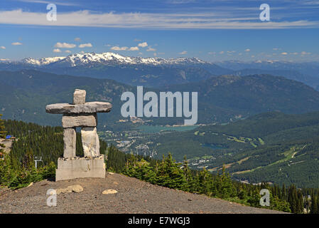 The Winter Olympic mascot the Inukshuk looks down on Whistler against a backdrop of snow-capped mountains. Stock Photo