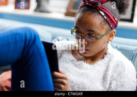 Mixed race teenage girl reading on a kindle Stock Photo