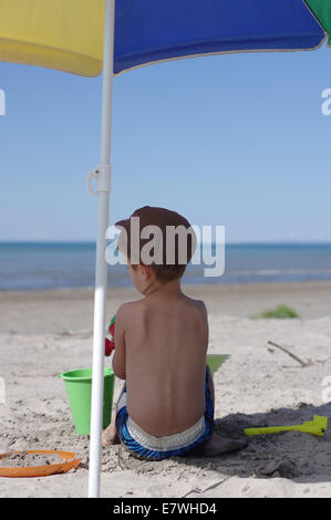 Small boy plays with the beach sand in the shade- lake Huron, Georgian bay Stock Photo