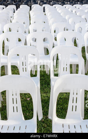 White plastic stackable lawn chairs in rows waiting for a crowd Stock Photo