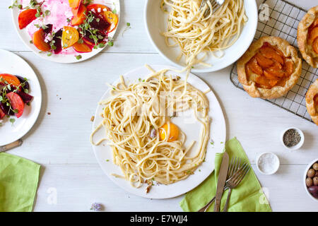 Messy spaghetti, beet salad, and apricot tart leftovers Stock Photo