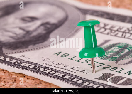 Green push pin with one hundred dollar bill on cork bulletin board. Stock Photo
