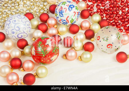 Christmas ornaments of different colors and sizes set in a random pattern along with red and gold colored beads on a silk cloth. Stock Photo
