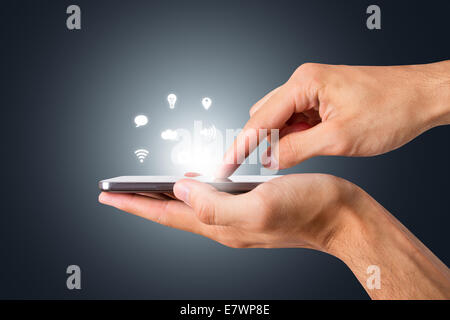 Hand hlding and touching smart phone with blank screen with social icons, side view on dark background. Stock Photo