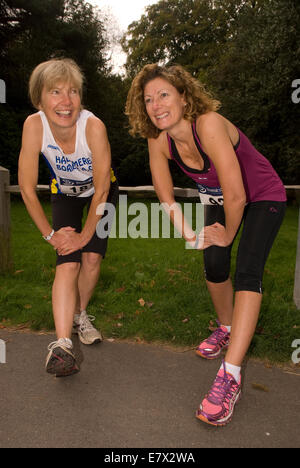 Two women doing stretching exercises/ warming up prior to a 10KM run for charity, Hindhead, Surrey, UK. Stock Photo