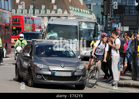 Traffic traveling around a corner into Parliament Square, London. Pedestrians wait to cross the road. Stock Photo