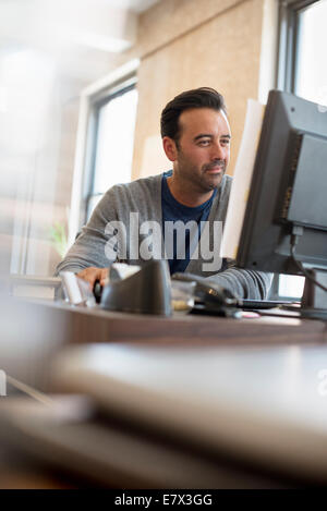 Man using his computer at his desk Stock Photo - Alamy
