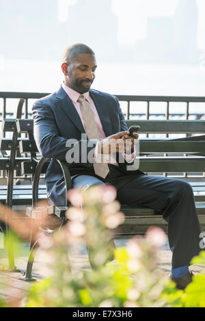 A businessman seated checking his phone, smiling.