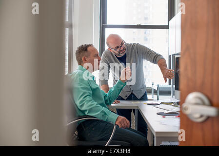 Two men in an office looking at a computer screen. Stock Photo