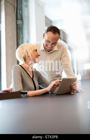 Office life. Two people sharing a digital table in an office. Stock Photo
