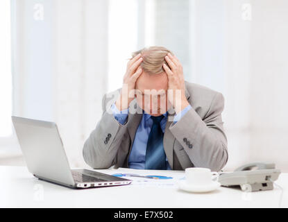 upset older businessman with laptop and telephone Stock Photo