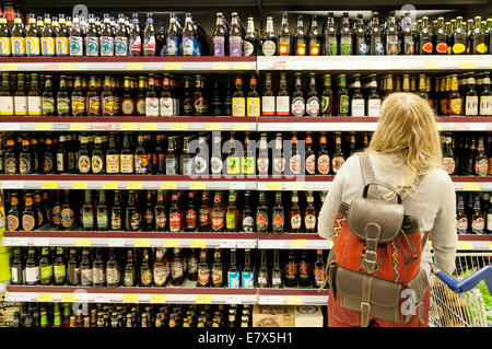 Blonde woman shopping for / buying bottled beer, Tesco supermarket, Newmarket Suffolk UK Stock Photo