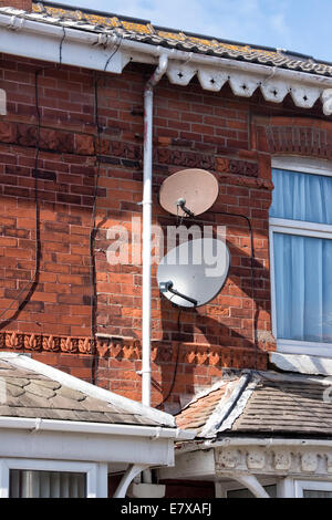 Two SKY TV  Satellite dishes (one very rusty) attached to a suburban house Stock Photo