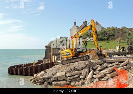 Cuckmere Haven, East Sussex, England. 25th September 2014. Heavy machinery takes to the beach to improve the coastal defences. Woollard Earth Moving Ltd are transporting huge rocks and rubble onto the shoreline adjacent to the coastguards cottages in an attempt to halt the effects of the sea. Strong tides and crashing waves are gradually eroding the limestone cliffs and eating away at the beach along this dramatic and picturesque stretch of the Sussex coast. Credit:  Julia Gavin UK/Alamy Live News Stock Photo