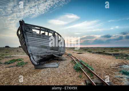 Old wooden fishing boat stranded on a shingle beach Stock Photo