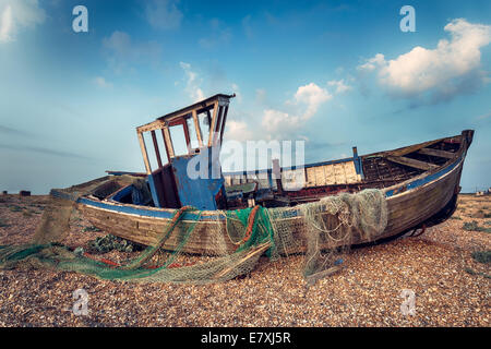 Old wooden fishing boat washed up on a shingle beach Stock Photo