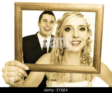 Wedding day. Portrait of happy bride woman girl and groom man couple in wooden frame isolated on white. Studio shot. Stock Photo