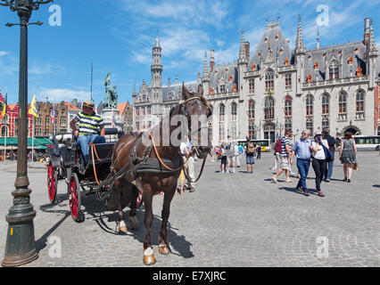 BRUGGE, BELGIUM - JUNE 13, 2014: The Carriage on the Grote Markt and the Provinciaal Hof building in background. Stock Photo