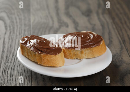 two baguette slices with cocoa nut spread, on wood table Stock Photo