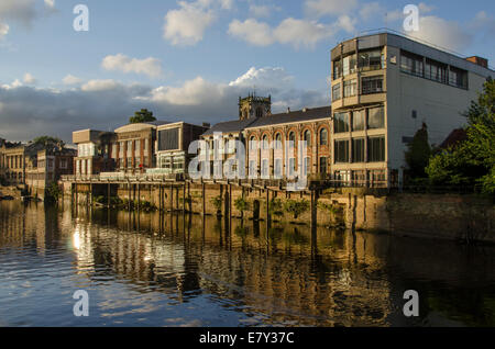 Scenic riverside buildings with long walkway balcony, lit by summer evening sun, reflected in the River Ouse - York, North Yorkshire, England, UK. Stock Photo