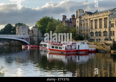 City cruise boats moored in summer evening sun by Guildhall & Lendal Bridge - view from south bank of River Ouse, York, North Yorkshire, England, UK. Stock Photo