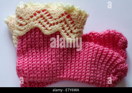 hand knitted pink slippers socks with lacy tops set on white background Stock Photo