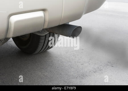 A car emits carbon monoxide gas from its exhaust tailpipe, showing how pollution is formed. Stock Photo