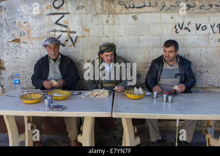 Kurdish men, wearing traditional clothing, having lunch at the bazaar, in Erbil (Arbil), Iraqi Kurdistan province, Iraq. Stock Photo