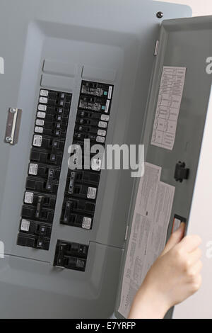 Coquitlam, BC, Canada - June 15, 2014 : Woman turning off the light-switch in the hall at home. Stock Photo