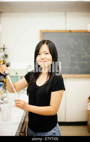 Woman in laboratory using pipette filler and glass tube Stock Photo