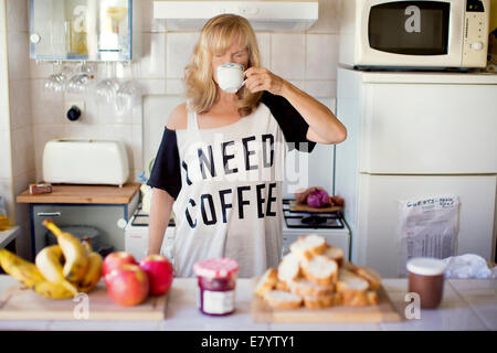 Woman drinking coffee in kitchen Stock Photo