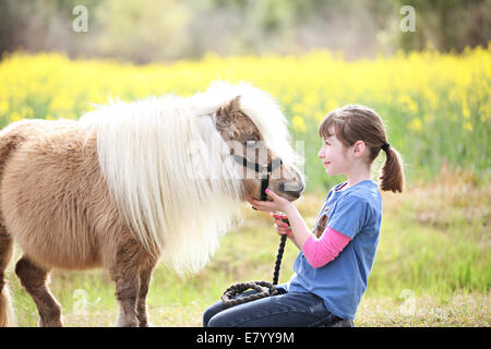Girl (10-12) playing with pony in meadow Stock Photo