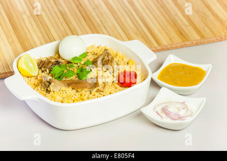 Full view of delicious mutton (lamb) biryani garnished with tomato peel, cilantro and lemon. Stock Photo