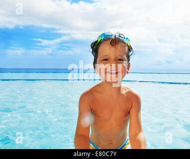 Portrait of cute boy with goggles standing in sea