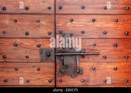 Old red wooden door with metal lock and bolt. Stock Photo