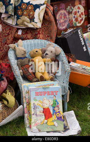 Vintage retro Stall with Rupert the bear annuals and Cuddly Toys in a wicker chair Stock Photo