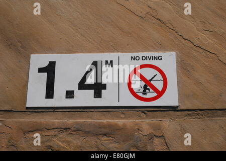 Information about water depth and a no-diving warning at the edge of a swimming pool in Kingdom of Bahrain Stock Photo