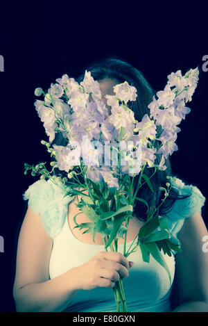 Woman holding flowers in front of her face Stock Photo