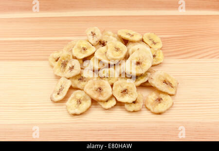 Pile of dried banana chips on a wood grain background Stock Photo
