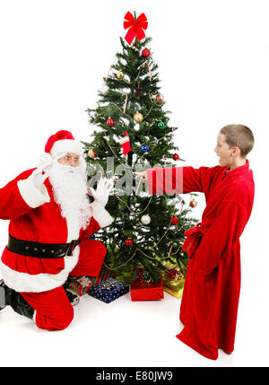 Little boy surprises Santa Claus on Christmas morning.  Isolated on white. Stock Photo