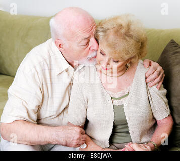 Elderly husband kissing his wife on the cheek in a gesture of consolation and love. Stock Photo