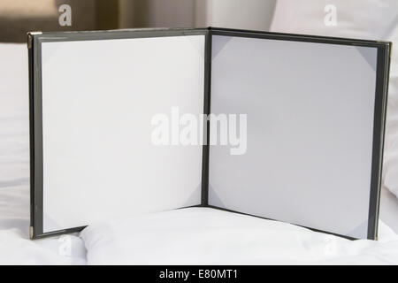 Blank white note paper, sheets on bed in hotel room. Stock Photo