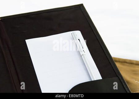 White blank note with pen on bed in hotel room. Stock Photo
