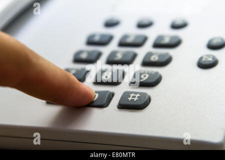 Finger pressing phone key, telephone for customer service in hotel room. Stock Photo