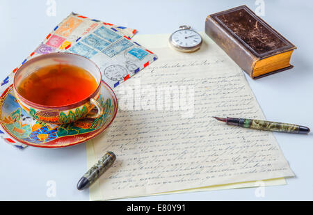 Vintage scene of old handwritten letter, us airmail envelopes, antique fountain pen, pocket watch, chinese porcelain, tea cup Stock Photo