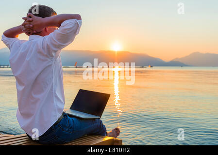Recreational entrepreneur. Man with laptop in the morning on the beach working Stock Photo