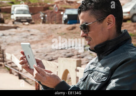 Horizontal portrait of an attractive Moroccan taking pictures on a tablet in the High Atlas Mountain range in Morocco. Stock Photo